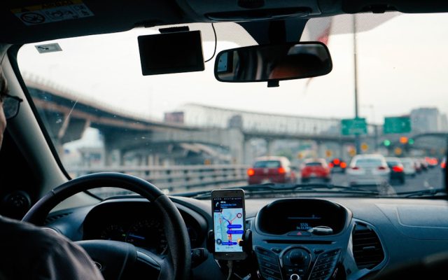 Smartphone navigation app mounted on a car dashboard in Georgia traffic, illustrating usage-based telematics auto insurance